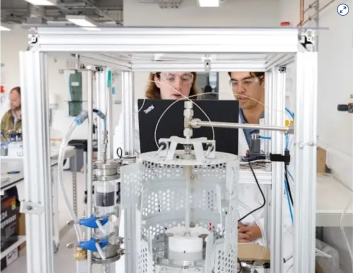 Two Lab workers observing a laptop in front of some lab equipment